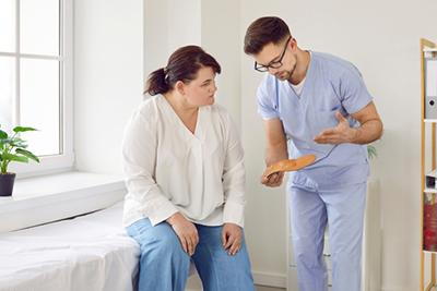 Podiatrist showing custom orthotic insoles to patient and explaining their role in foot alignment