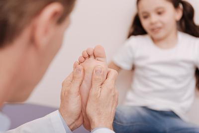 Doctor checking the condition of foot on a little girl