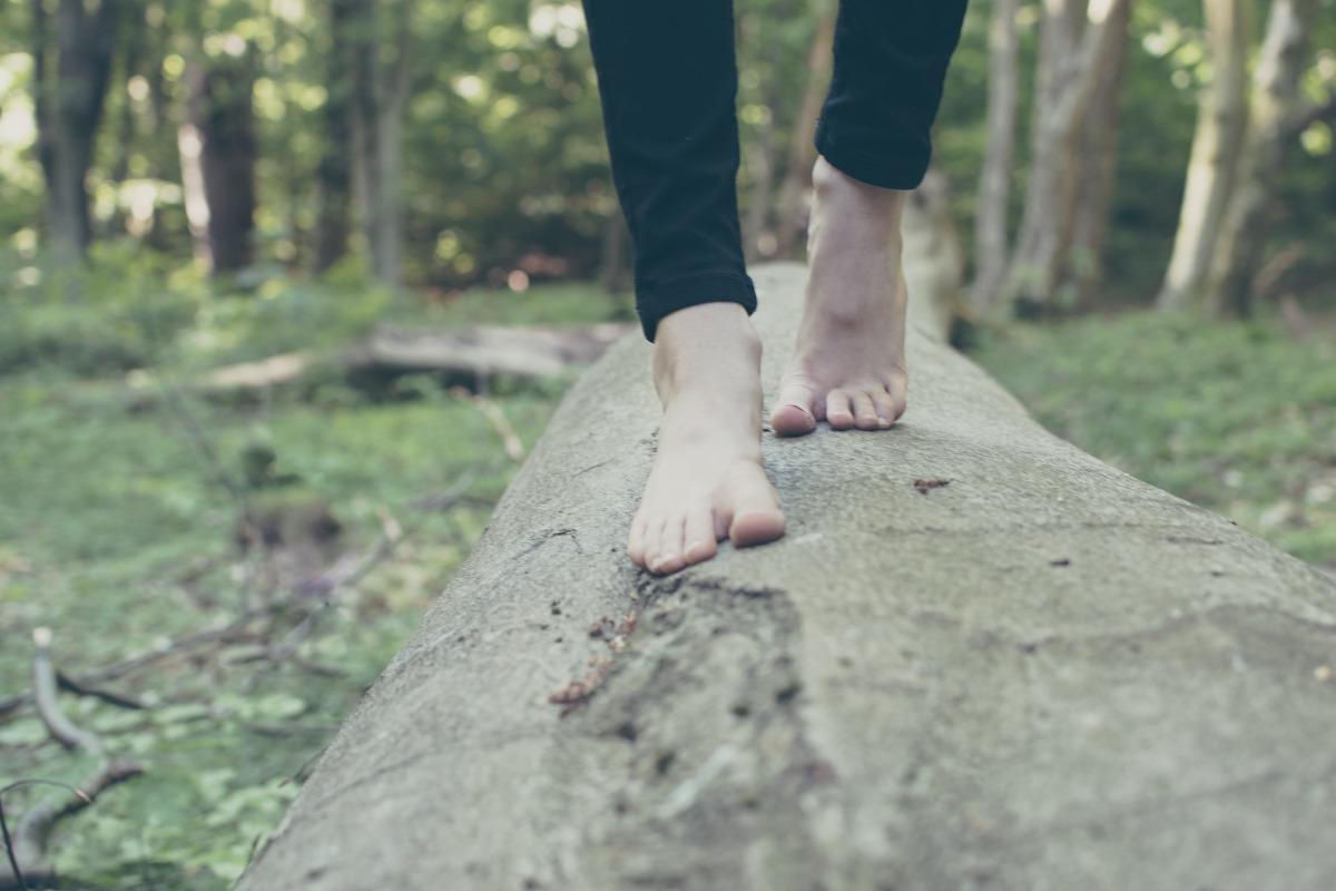 Woman walking barefoot on a tree log