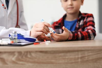Doctor pricking child’s finger for blood glucose test