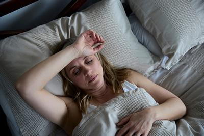 Tired woman lying in bed experiencing discomfort
