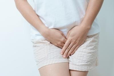 Female experiencing pelvic pain with hands pressed on lower abdomen