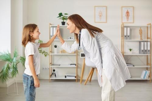 A child giving a high-five to a pediatrician after a routine physical examination.
