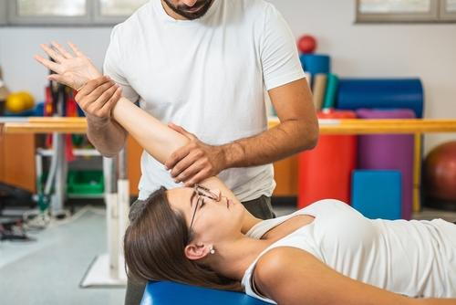 A chiropractor performing therapy to relieve joint pain in a client's limbs.