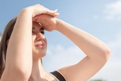 Young woman covering face to protect skin from sun exposure