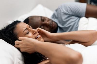 Woman covers ears annoyed by snoring partner