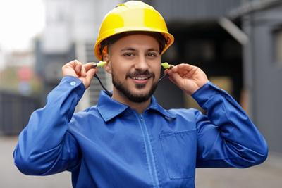 Worker putting on hearing protection to prevent noise-induced hearing loss.