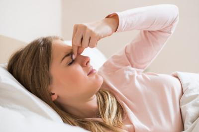 Young woman in bed holding nose due to sinus pain at night