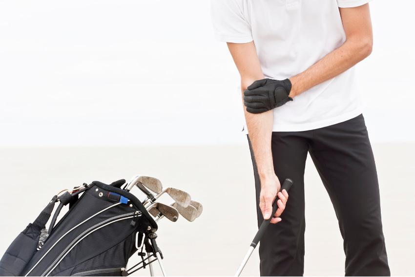 Man holding a golf club suffers from golfer's elbow pain