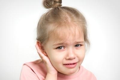 Young girl feeling in pain from ear infection.