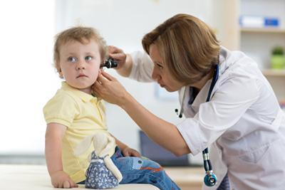 Doctor checking the ear of a young boy.
