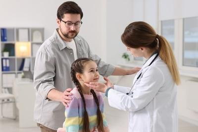 Female doctor check the young girl with her father on clinic