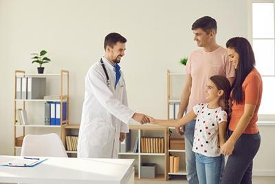 Physician warmly welcoming a family for their medical appointment