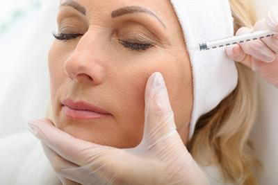 Injecting botox to an eye wrinkle of woman