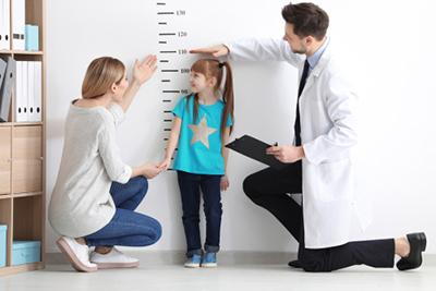 Parent smiling as pediatrician measures daughter’s growth