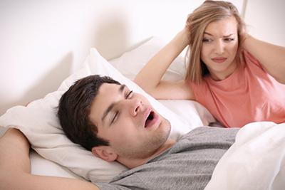 Couple in bed, woman annoyed by partner’s snoring