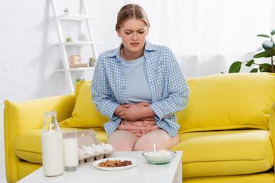 Woman holding her stomach in pain after drinking milk, indicating food intolerance.