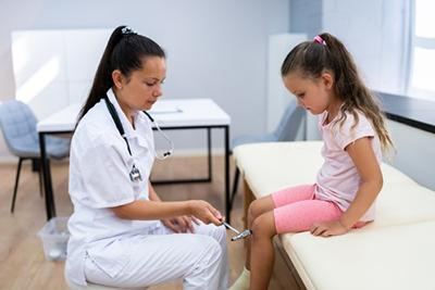 Doctor checking the knee of a young girl on clinic