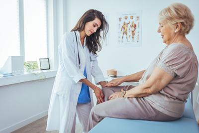 Therapist gently examining strained muscle in older woman