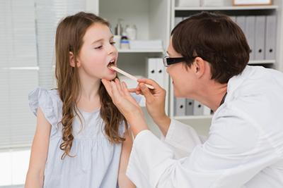 Pediatrician inspecting child’s throat during a check-up