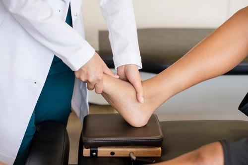 A patient's foot being examined by a podiatrist during a clinical evaluation.