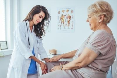 Doctor checking the knee of the senior patient.