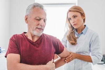 Therapist assisting the movement of a senior man for care