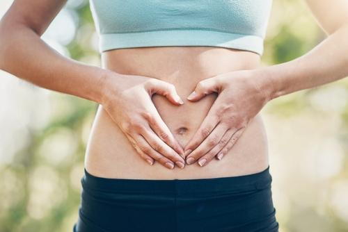 Woman outdoors holding her stomach to symbolize digestive comfort and gut health