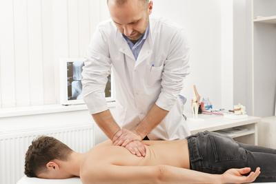 Chiropractor adjusting the back of patient on clinic.