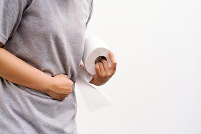 Man holding tissue with diarrhea on toilet.