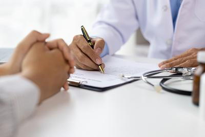 Doctor writting a notes to a patient infront of table