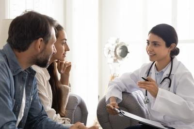 Doctor with notes talking to a couple on clinic