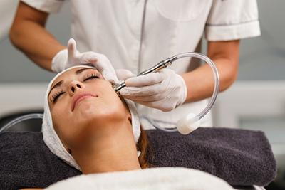 Female client undergoing dermabrasion facial treatment.