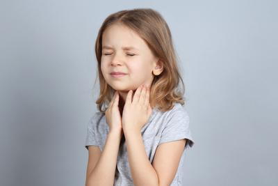 Little girl clutching her throat due to breathing difficulty