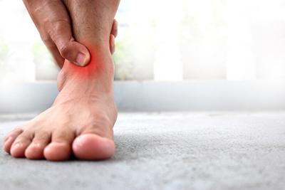 Person suffering in ankle pain highlight in red.