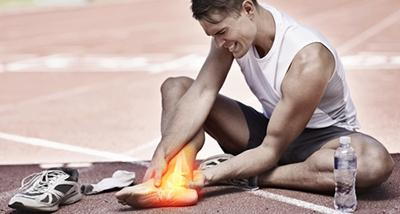 Runner suffering from foot and ankle injuries outdoor.