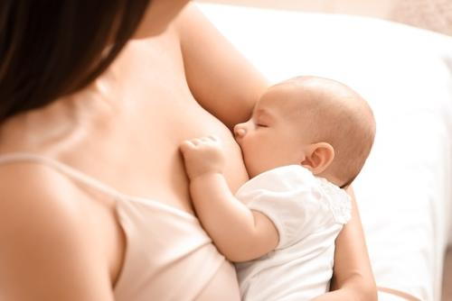 Parent breastfeeding newborn at home