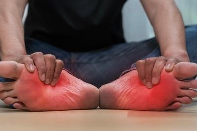 Man suffering from foot pain highlights with red