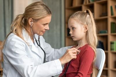 Doctor checking the girl on clinic with stesthoscope.