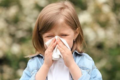 Young girl suffering from colds wiping her nose outdoor