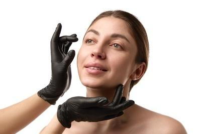 Flawless womans face with doctors hand on black gloves