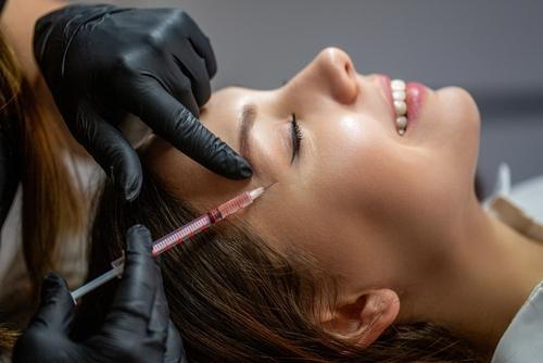 A woman receiving a Botox injection to reduce crow's feet wrinkles around the eyes.