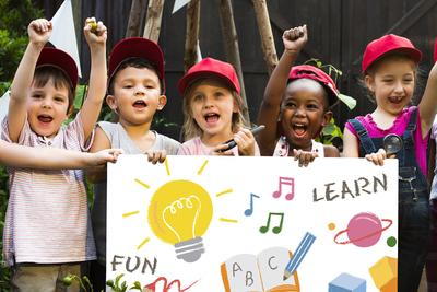 Children holding a learning sign and cheering outdoors
