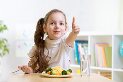 Young girl having thumbs up while eating a healthy food.