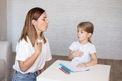 Therapist teaching the girl a pronouciation on room