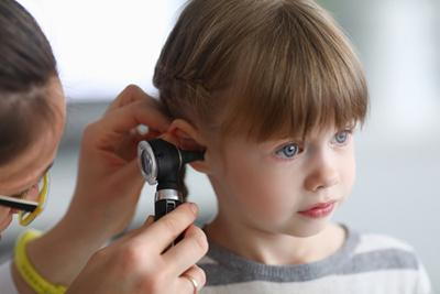 Doctor checking the ear of a young girl with blue eyes