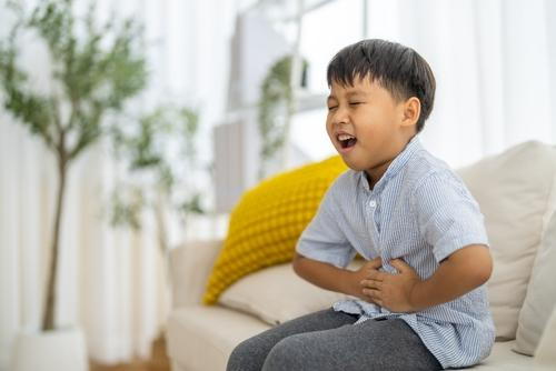 Young boy feeling in pain on abdomen while sitting on sofa
