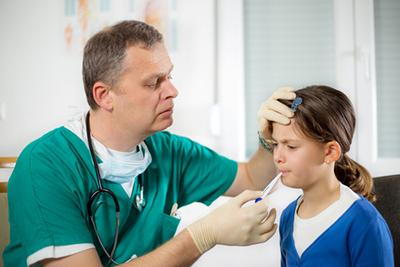 Doctor checking the temperatures of a young girl.