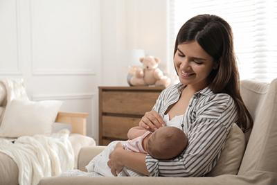 Mother breastfeed her baby while sitting on sofa