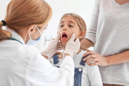 Child being examined by a doctor for a sore throat